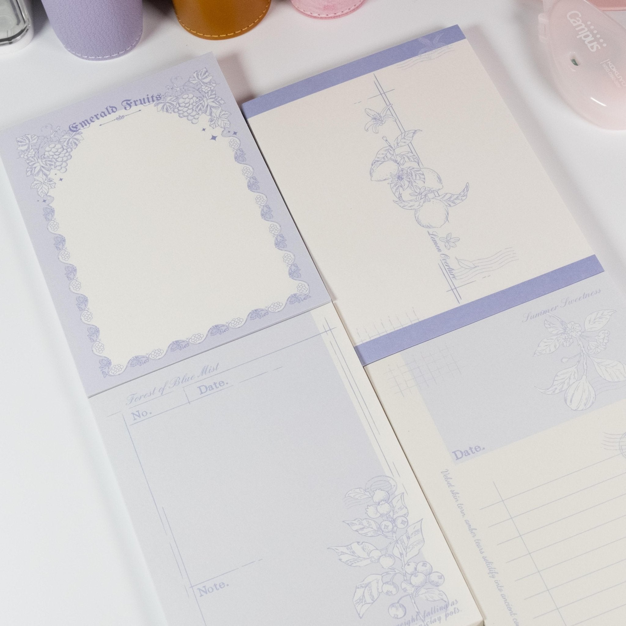 Flat lay of all four Floral Fruits A6 notepad designs featuring flowers and fruits in watercolour tones - Miouva