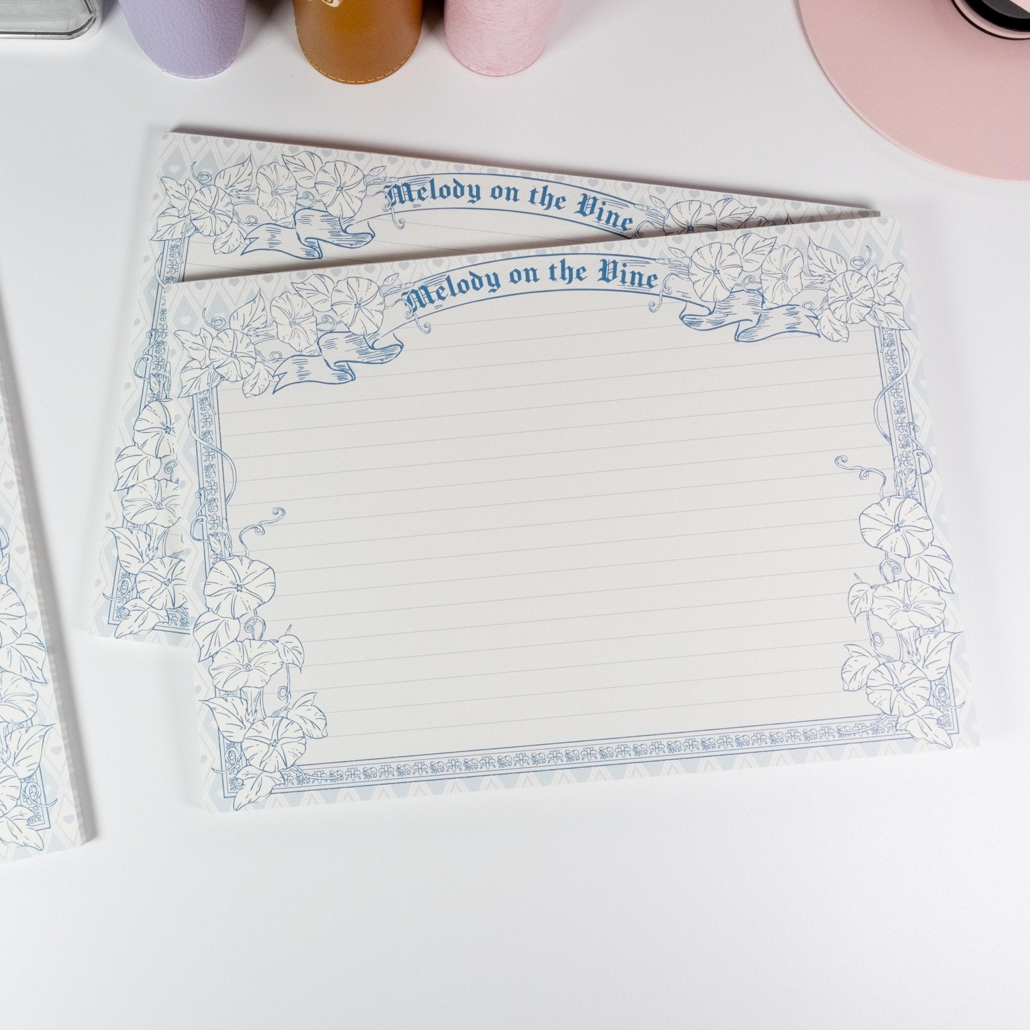 Horizontal B5 notepad flat lay showing lined page with floral frame - Miouva