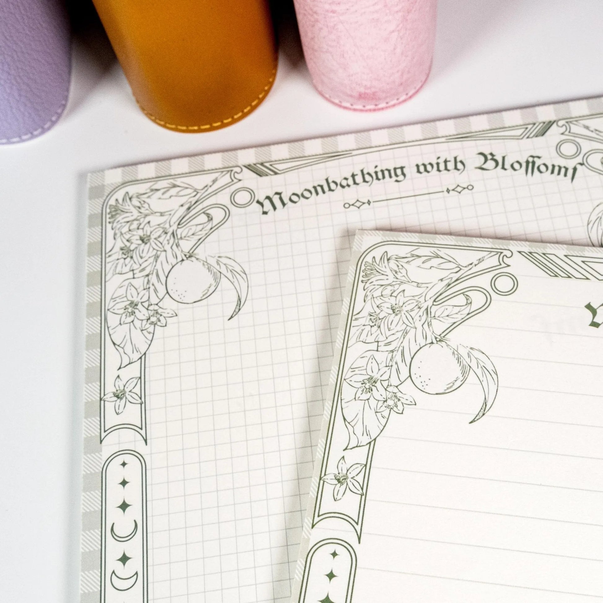 Horizontal B5 notepad open showing lined page with citrus blossom frame - Miouva