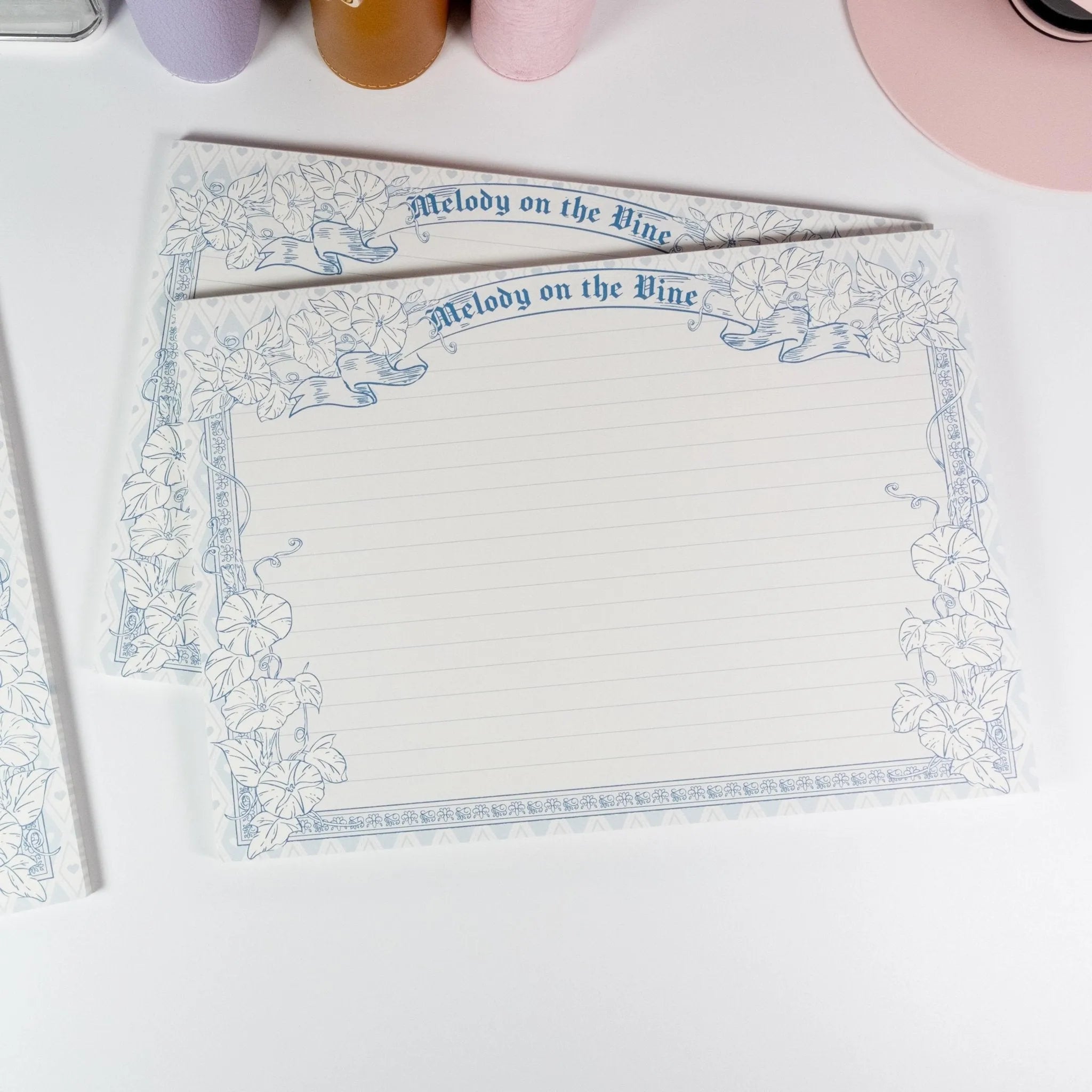 Horizontal B5 notepad flat lay showing lined page with floral frame - Miouva